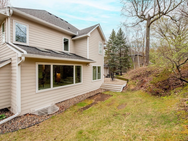 view of side of property featuring a yard, roof with shingles, and a wooden deck