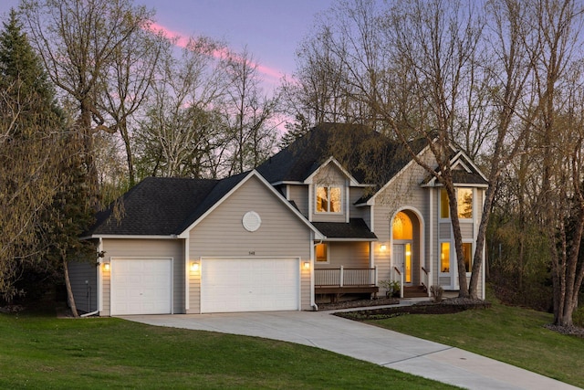 traditional-style house with concrete driveway, a yard, roof with shingles, and a garage