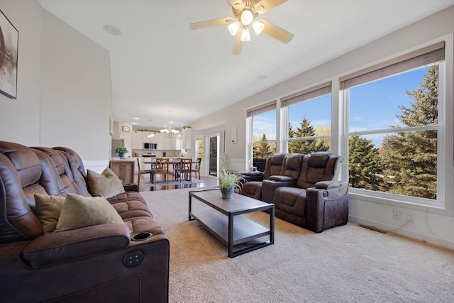 living area featuring visible vents, light carpet, and ceiling fan with notable chandelier