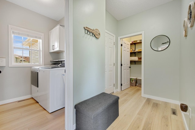 laundry room with cabinet space, baseboards, light wood-type flooring, visible vents, and washing machine and dryer
