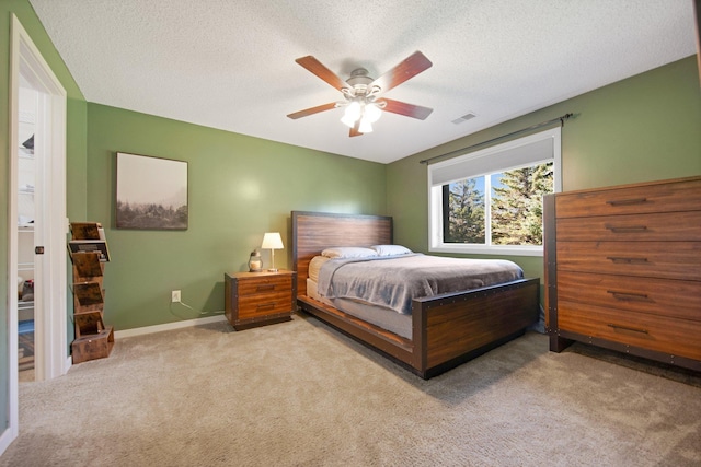 carpeted bedroom featuring visible vents, a ceiling fan, baseboards, and a textured ceiling