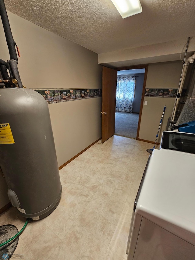 interior space featuring a textured ceiling, washer / clothes dryer, range, baseboards, and water heater