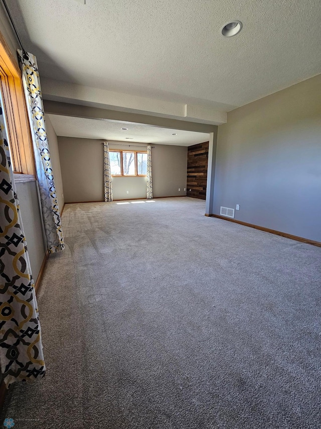unfurnished room featuring carpet flooring, a textured ceiling, and visible vents