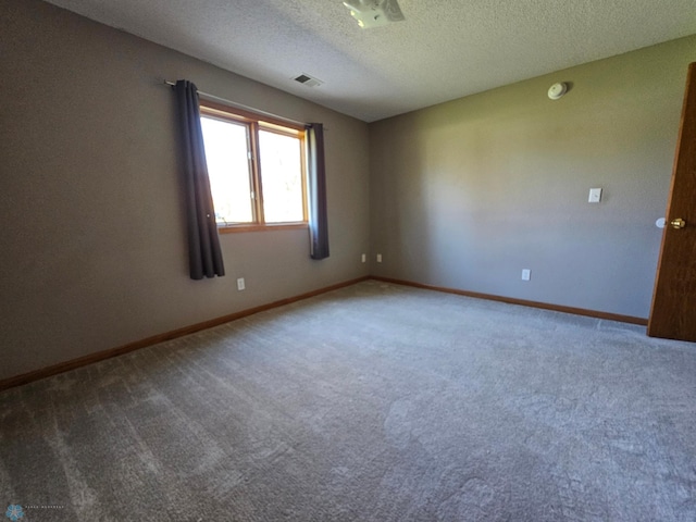spare room with carpet floors, a textured ceiling, baseboards, and visible vents