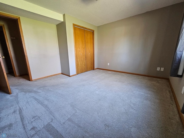 unfurnished bedroom featuring baseboards, a textured ceiling, carpet, and a closet