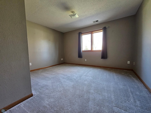 empty room with a textured ceiling, visible vents, baseboards, a textured wall, and carpet flooring