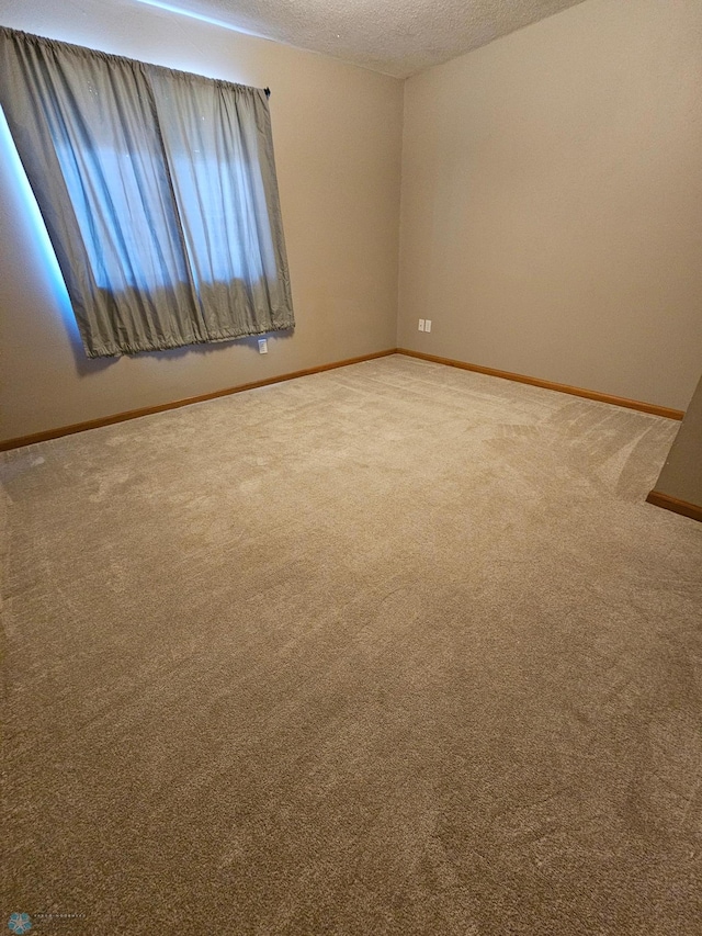 carpeted spare room with baseboards and a textured ceiling