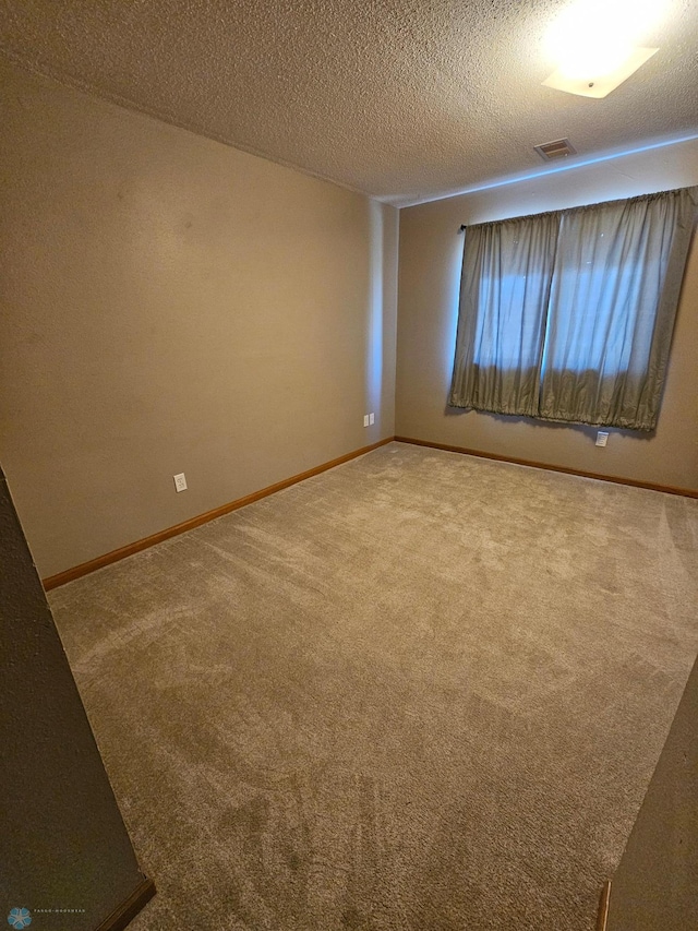 spare room with baseboards, visible vents, and carpet