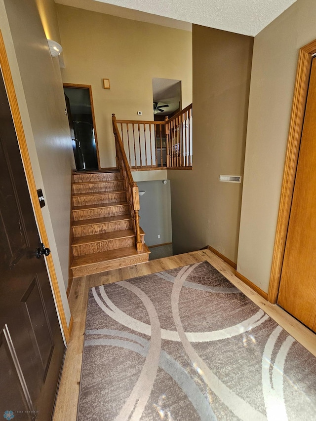 stairs with baseboards, a ceiling fan, and wood finished floors