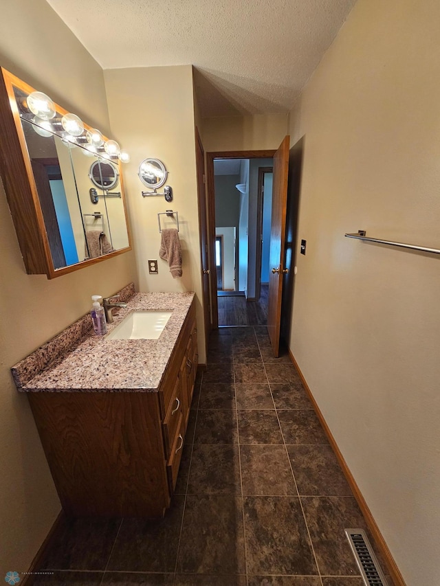 bathroom with vanity, baseboards, a textured ceiling, and visible vents