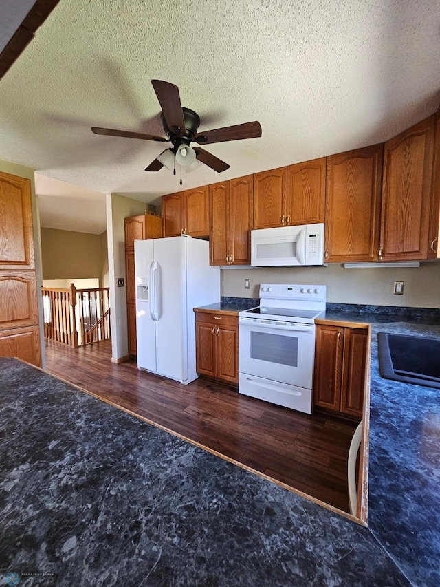 kitchen with white appliances, ceiling fan, brown cabinetry, and a sink