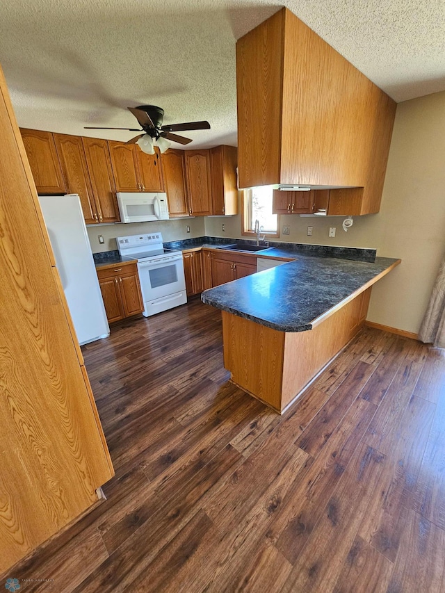 kitchen with a textured ceiling, a peninsula, brown cabinets, and white appliances