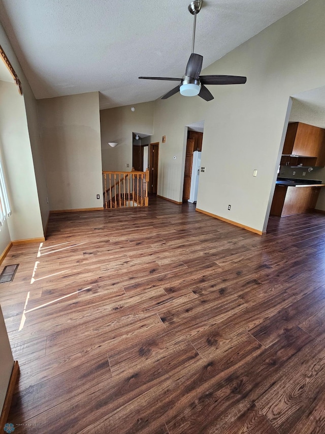 unfurnished living room featuring a textured ceiling, vaulted ceiling, wood finished floors, and visible vents