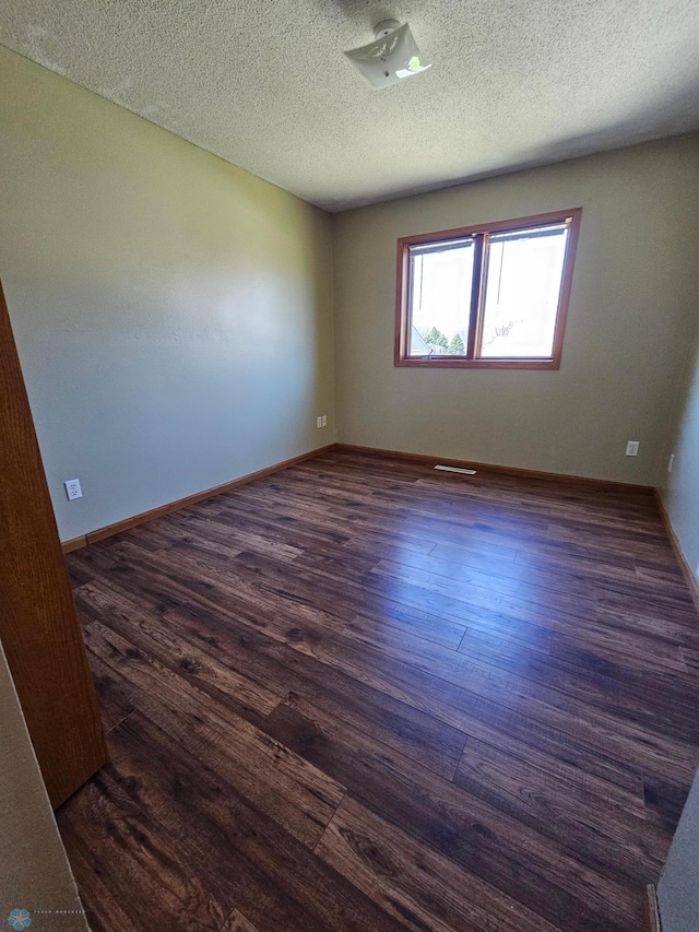 unfurnished room with baseboards, a textured ceiling, and dark wood-style floors