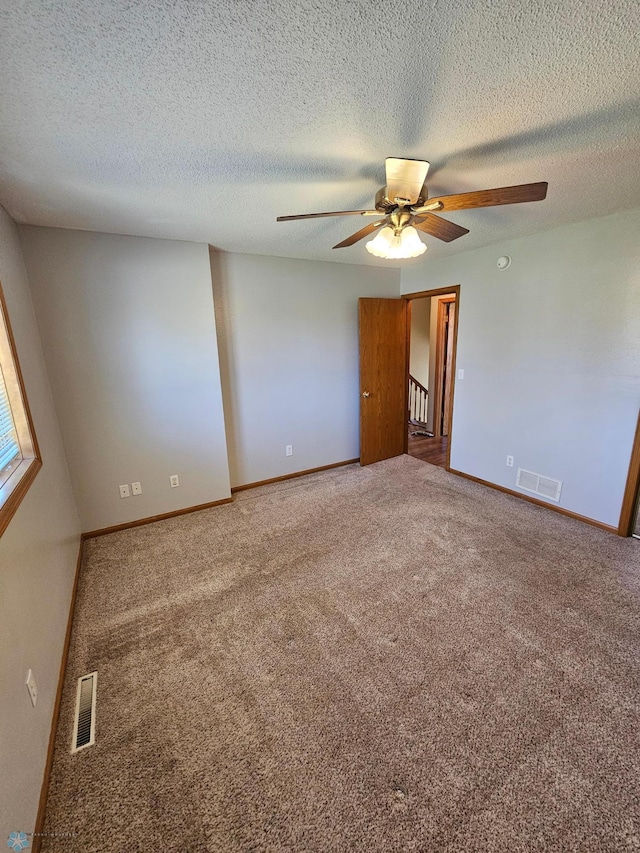 carpeted spare room with a ceiling fan, baseboards, and visible vents