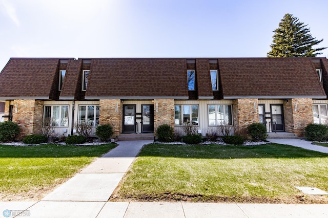 multi unit property featuring brick siding, a shingled roof, and a front yard