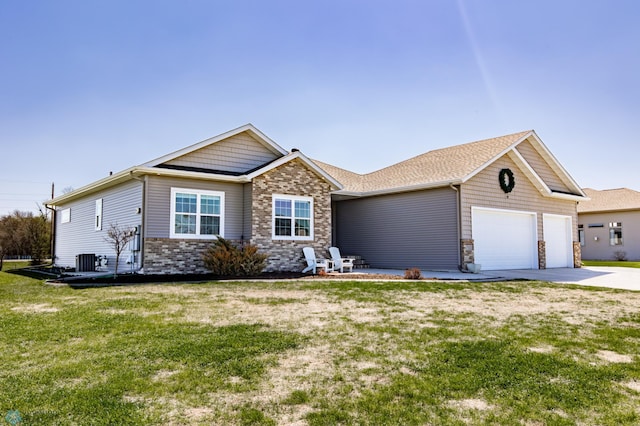 view of front of house featuring an attached garage, stone siding, driveway, central AC, and a front yard