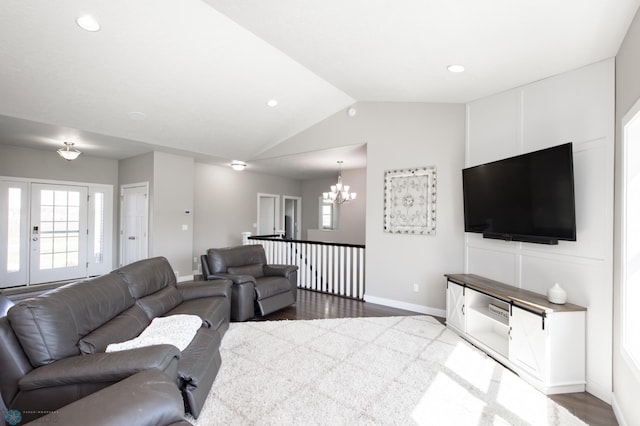 living room with lofted ceiling, a wealth of natural light, a notable chandelier, and baseboards