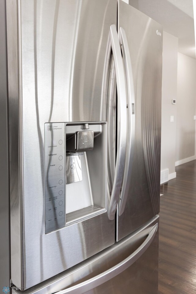 room details with dark wood-style flooring, baseboards, and stainless steel refrigerator with ice dispenser