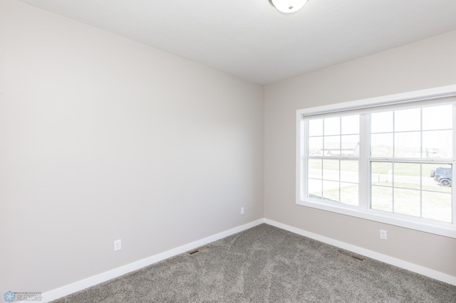 empty room with carpet flooring, baseboards, and visible vents