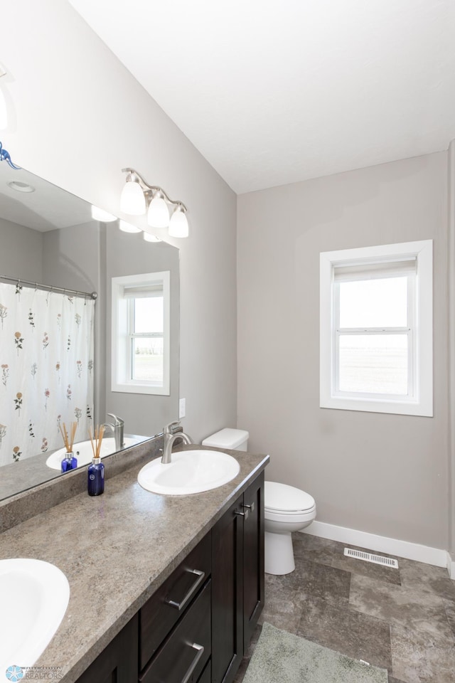 bathroom with toilet, double vanity, baseboards, and curtained shower