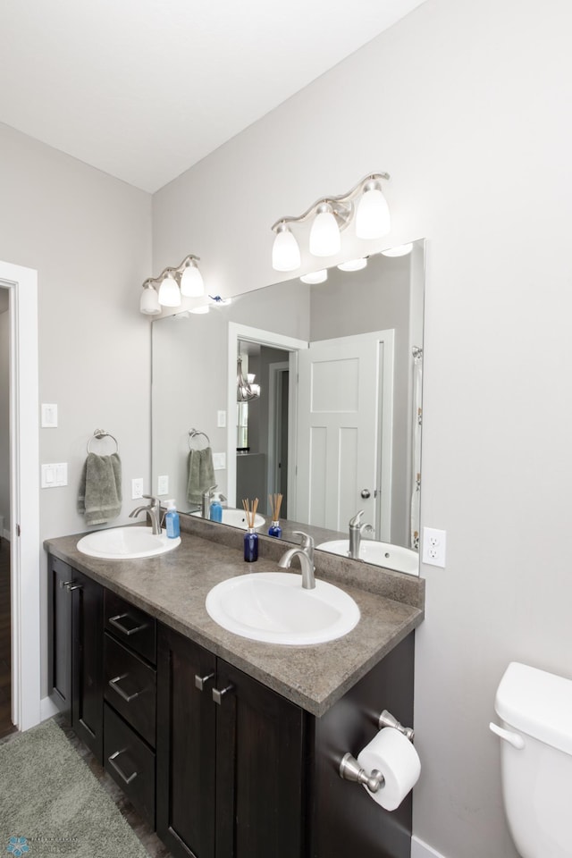 full bathroom with a sink, double vanity, and toilet