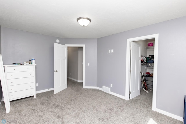 unfurnished bedroom featuring a walk in closet, carpet floors, baseboards, and visible vents
