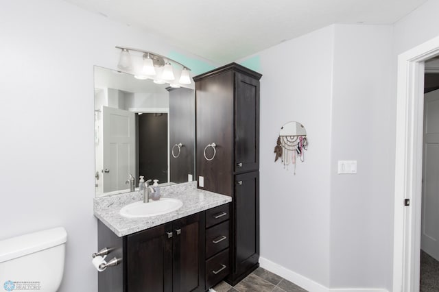 bathroom with toilet, baseboards, and vanity