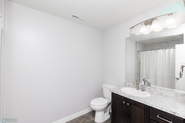 bathroom with baseboards, toilet, and vanity