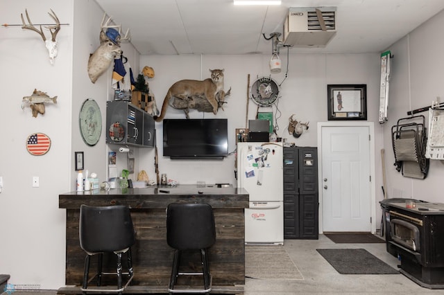 indoor bar featuring freestanding refrigerator, a wood stove, and a heating unit