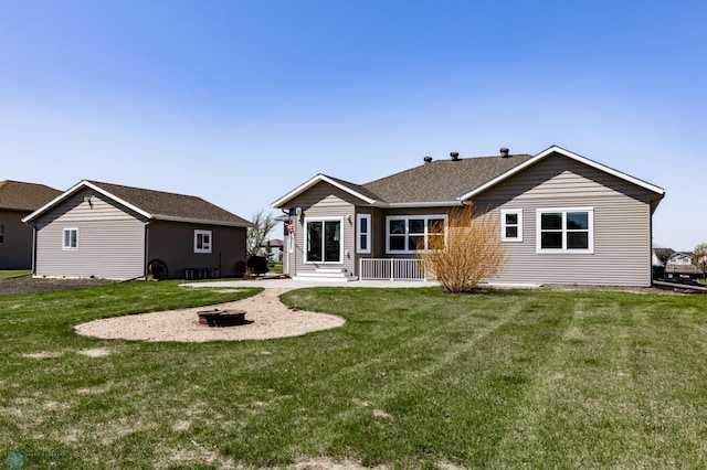 back of property with a lawn, a patio area, and an outdoor fire pit