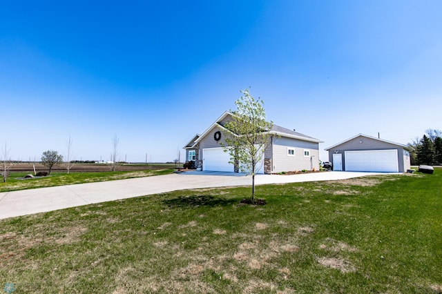 view of front of house with a front yard, an outdoor structure, driveway, and a detached garage