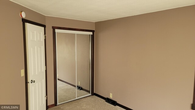 unfurnished bedroom with baseboards, carpet, and a closet