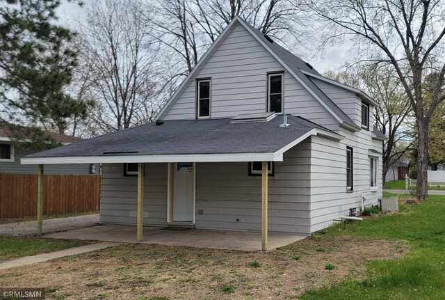 back of house featuring fence, a shingled roof, and a patio area