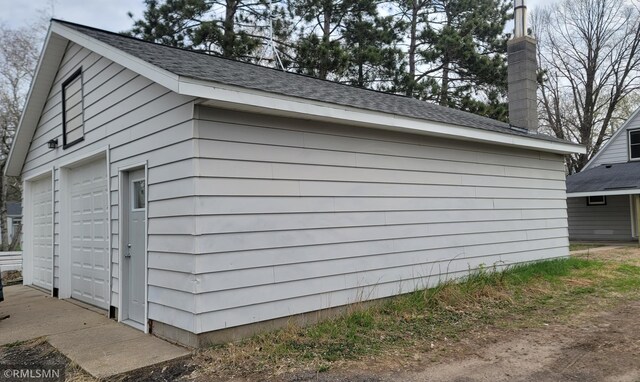 view of property exterior featuring a detached garage and an outdoor structure