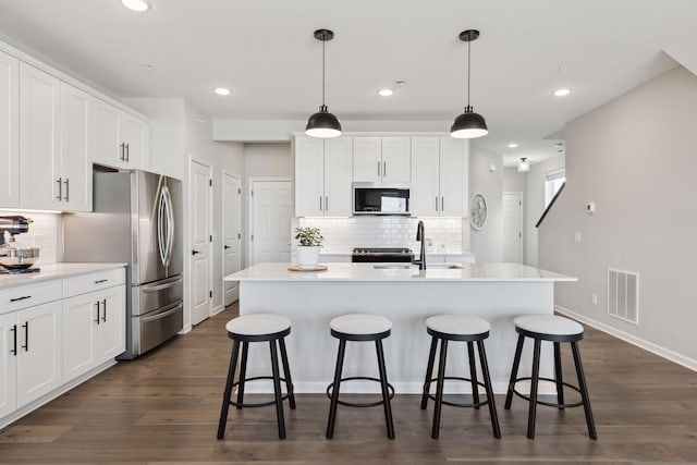173 Junco Rd N, Lake Elmo, MN 55042 - kitchen with freestanding refrigerator, decorative backsplash, white cabinets, a kitchen bar, and recessed lighting