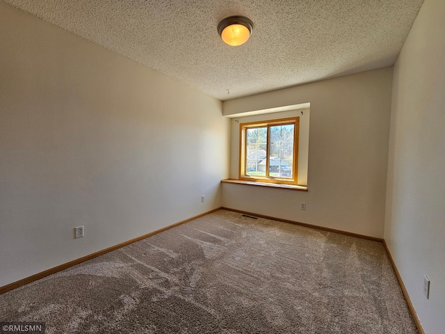 carpeted empty room with visible vents, a textured ceiling, and baseboards