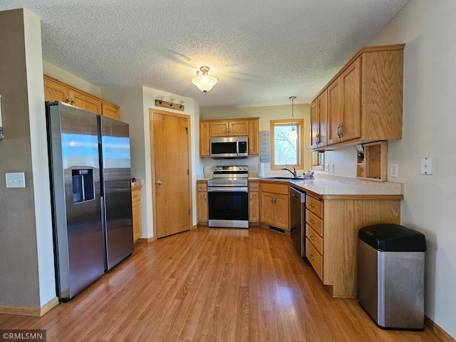 kitchen featuring light countertops, baseboards, appliances with stainless steel finishes, and light wood finished floors