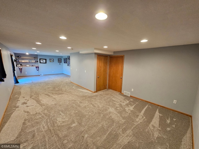 finished below grade area with visible vents, carpet flooring, and recessed lighting