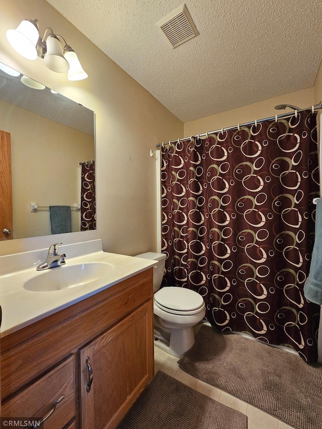bathroom with visible vents, tile patterned flooring, vanity, toilet, and a textured ceiling
