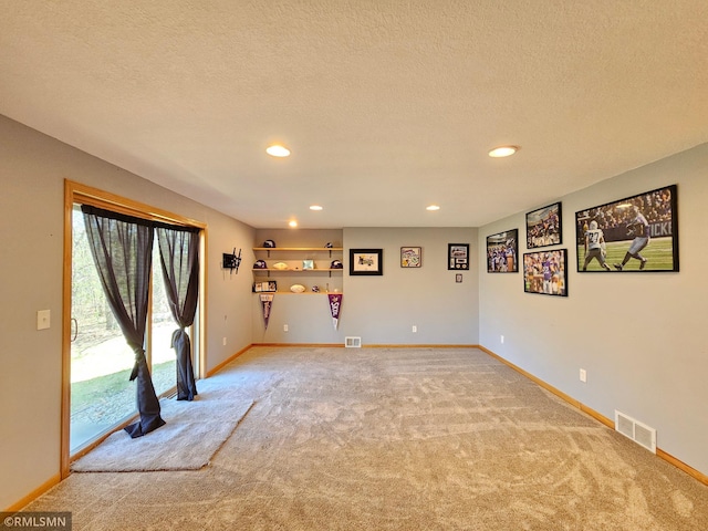 spare room featuring visible vents, a textured ceiling, baseboards, and light carpet