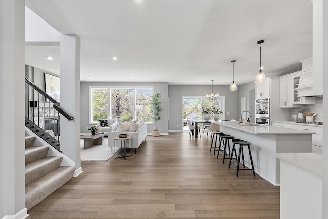 living room featuring wood finished floors, plenty of natural light, stairs, recessed lighting, and baseboards