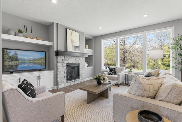 living area featuring wood finished floors, a fireplace, recessed lighting, and a textured ceiling