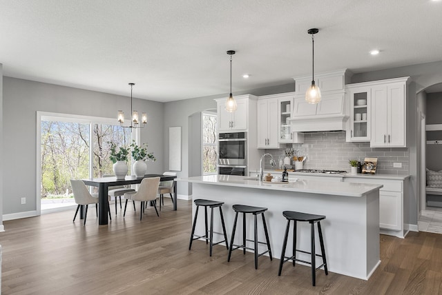 kitchen with a sink, arched walkways, backsplash, appliances with stainless steel finishes, and recessed lighting