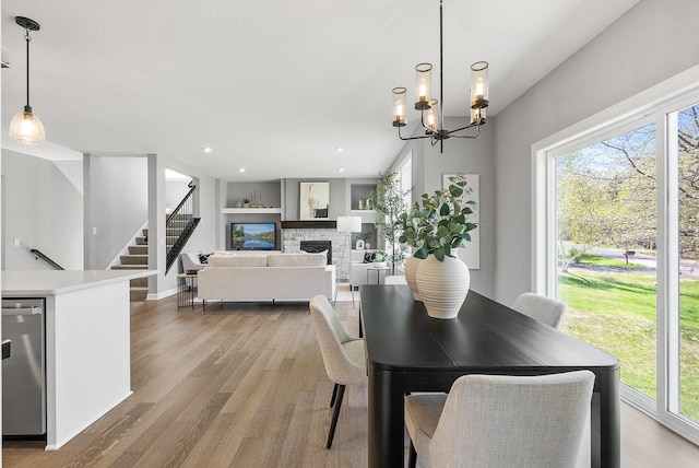 dining space featuring plenty of natural light, a fireplace, wood finished floors, stairway, and recessed lighting