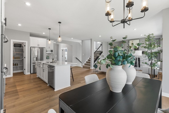 dining area featuring stairway, wood finished floors, recessed lighting, arched walkways, and a chandelier