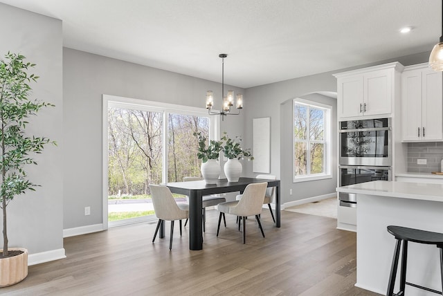 dining area featuring baseboards, light wood-type flooring, and a chandelier