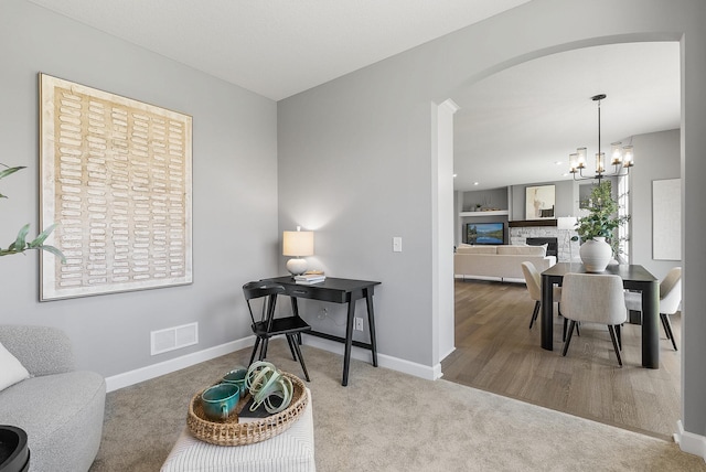 sitting room with baseboards, a chandelier, carpet floors, arched walkways, and a fireplace