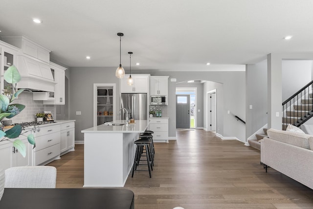 kitchen with stainless steel appliances, a sink, arched walkways, tasteful backsplash, and recessed lighting