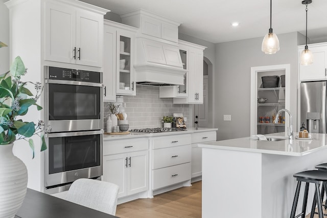 kitchen with stainless steel appliances, a sink, decorative backsplash, light countertops, and recessed lighting